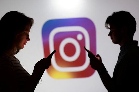 Teenagers pose for a photo while holding smartphones in front of an Instagram logo on September 11, 2025. DADO RUVIC / REUTERS