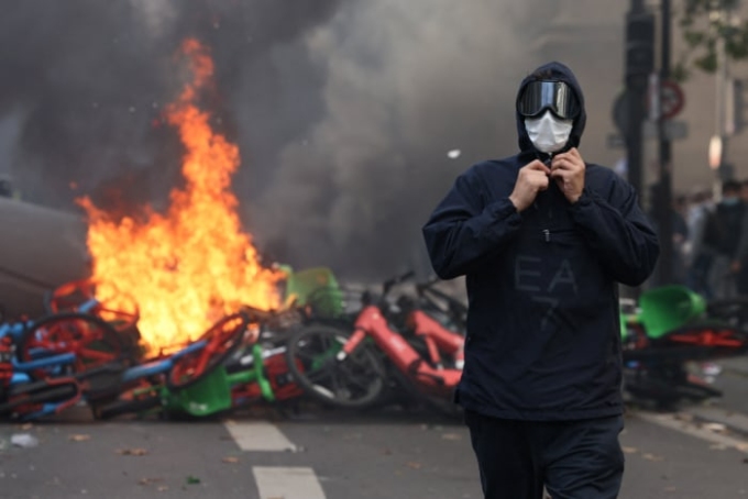 A masked protester walks past burning bicycles in Paris on Saturday. JACK TAYLOR/REUTERS