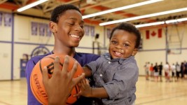 Elijah Fisher, with a basketball in one hand and his younger brother, Daniel, in the other. (Tina Mackenzie/CBC)