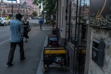 People walking past generators lined up outside some businesses. Generators powering a row of shops in the Podil neighborhood of Kyiv, Ukraine’s capital, on Tuesday.Credit...Brendan Hoffman for The New York Times