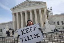 A protester waits with a placard as justices hear a bid by TikTok and its China-based parent company, ByteDance, to block a law intended to force the sale of the short-video app by Jan. 19 or face a ban on national security grounds, at the Supreme Court,