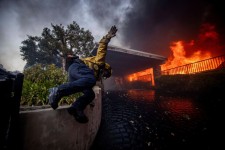 A firefighter jumps over a fence in Los Angeles's Pacific Palisades neighbourhood while fighting the wildfire Tuesday. (Ethan Swope/The Associated Press)