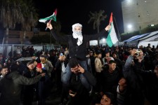 A man waves Palestinian flags as Palestinians react to news of a ceasefire deal with Israel on Wednesday in Deir Al-Balah, in the central Gaza Strip. (Ramadan Abed/Reuters)