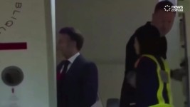 A pair of hands can be seen pushing French President Emmanuel Macron moments before the first couple were due to disembark from their flight.