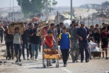 Des Palestiniens déplacés portent des paquets et d’autres denrées récupérés dans un centre de distribution d’aide de la bande de Gaza le 26 juillet 2025. EYAD BABA / AFP