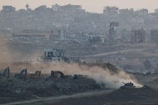 An Israeli tank near heavy machinery, with Gaza visible in the background. Photo: amir cohen/Reuters