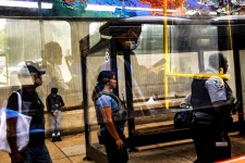 Passengers are reflected on glass as police officers patrol the Anacostia bus station in Washington, DC, on August 20, 2025.  Jose Luis Gonzalez/Reuters