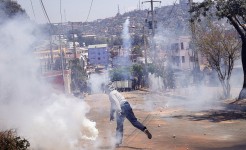 A protester throws back a tear gas canister lobbed by riot police during a demonstration denouncing frequent power outages and water shortages, near the University of Antananarivo, Madagascar, on Monday. Zo Andrianjafy/Reuters