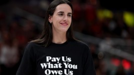 Indiana Fever guard Caitlin Clark wearing a shirt that says "Pay us what you owe us."Steph Chambers/Getty Images