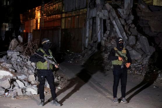 Des militants du Hamas montent la garde tandis que des véhicules de la Croix-Rouge transportent les corps d’otages remis à Israël dans le cadre de l’accord de cessez-le-feu, le 15 octobre 2025. DAWOUD ABU ALKAS / REUTERS