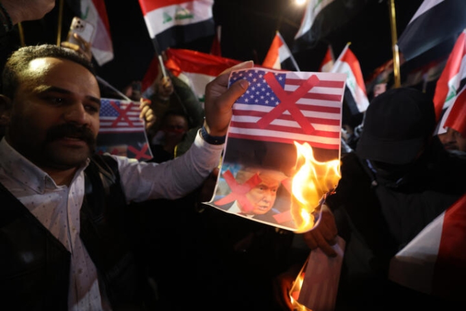 Des partisans de Nouri al-Maliki brûlent une photo du président américain Donald Trump et le drapeau américain à Bagdad, le 28 janvier 2026. © Ahmad al-Rubaye, AFP