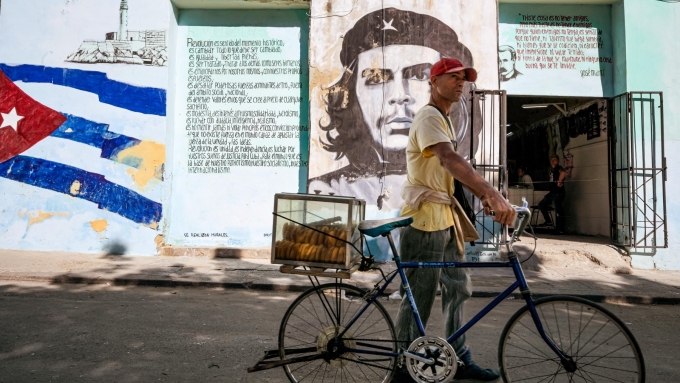 Un homme vend des pâtisseries devant une fresque murale qui représente Che Guevara, héros de la révolution cubaine, à La Havane, le 6 janvier 2026.  Photo : Getty Images / ADALBERTO ROQUE