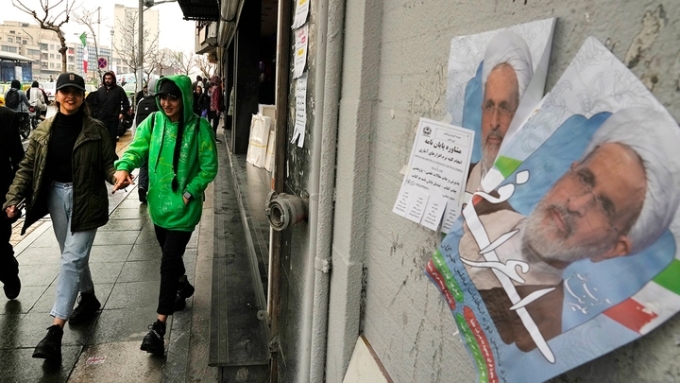 Women walk past electoral posters of Ayatollah Alireza Arafi in downtown Tehran, Iran, Feb. 21, 2024. (Vahid Salemi/AP Photo)