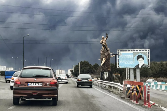 Plumes of black smoke mix with rain clouds in the skies of Tehran. © AFP