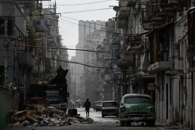 A man walks in the rain in Havana on Tuesday as workers restored electricity to much of Cuba after a total blackout. (Norlys Perez/Reuters)