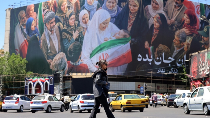 Une femme traverse une rue devant un grand panneau d'affichage politique près de la place Enghelab, dans le centre de Téhéran, le 26 mai 2026.  Photo : Getty Images / ATTA KENARE