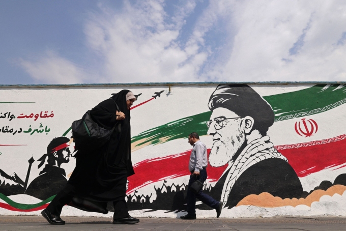 Pedestrians walk past a wall mural of Iran's slain supreme leader Ayatollah Ali Khamenei, along a street in downtown of Tehran on August 31.  Atta Kenare/AFP/Getty Images
