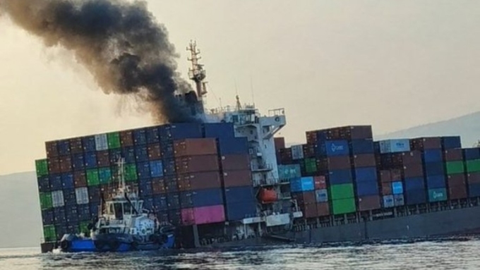 Smoke rises from the listing container ship GFS Pride after it struck a mine in the Strait of Hormuz on October 14, 2026. ©  Social media