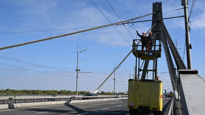 AFP via Getty Images / Technicians are repairing overhead trolleybus power lines on Kyiv's Pivnichnyi (Northern) Bridge