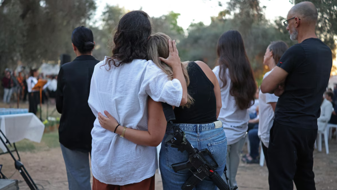 Des Israéliens s'étreignent lors d'une cérémonie d'hommage organisée au kibboutz Kfar Aza, dans le sud d'Israël, le 7 octobre 2026.  Photo : Getty Images / ILIA YEFIMOVICH