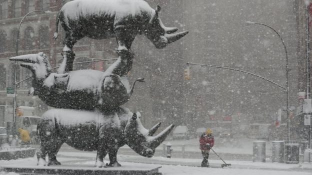 EPA / A worker clears snow near "The Last Three" sculpture in New York