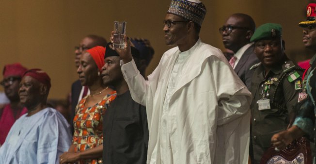 © Stefan Huenis / AFP | Nigerian president Muhammadu Buhari (C) proposes a toast in Lagos, on March 29, 2018.