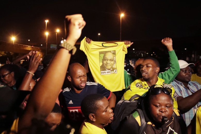 Supporters of former president Jacob Zuma hold a tee-shirt with his picture, attend a night vigil on the eve of Zuma's appearance in the High Court in Durban, South Africa, Thursday, April 5, 2018. Former South African president Jacob Zuma has been s
