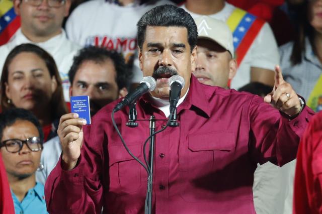 Venezuela's President Nicolas Maduro, holding a copy of the country's constitution, addresses supporters at the presidential palace in Caracas, Venezuela, after electoral officials declared he was re-elected on Sunday, May 20, 2018. (AP Phot