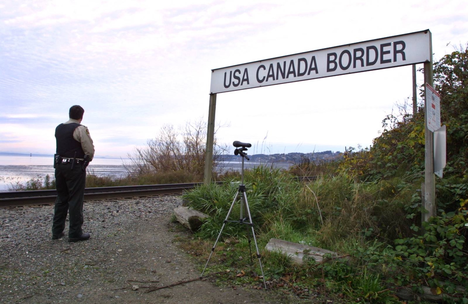 A Canadian Customs and Fisheries officer watches over the U.S.-Canada border between Blaine, Washington and White Rock, British Columbia November 8, 2001. (Photo by Jeff Vinnick/Getty Images)
