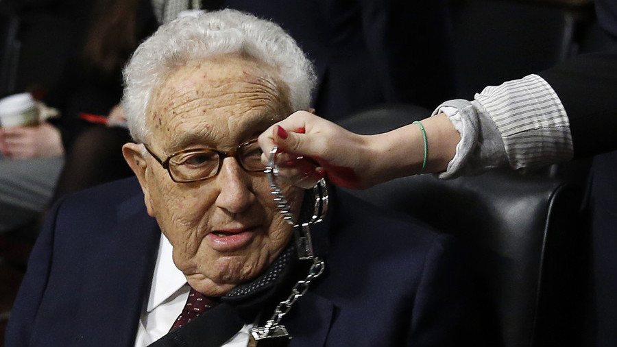 A demonstrator dangles handcuffs in front of Henry Kissinger at an earlier protest in Washington DC © Reuters / Gary Cameron