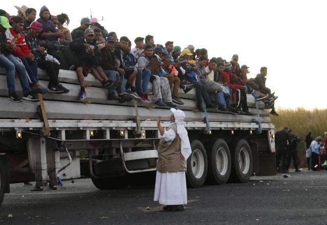 A Catholic nun gives travel advice to Central American migrants riding in the bed of a semi-trailer, as they move toward the U.S. border, in Ixtlán del Rio, Nayarit, Mexico, Tuesday, Nov. 13, 2018. The U.S. government said it was starting work Tuesday to