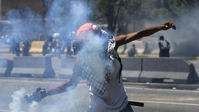 An opposition demonstrator throws a tear gas canister during clashes with soldiers loyal to Venezuelan President Nicolas Maduro. Picture: AFPSource:AFP