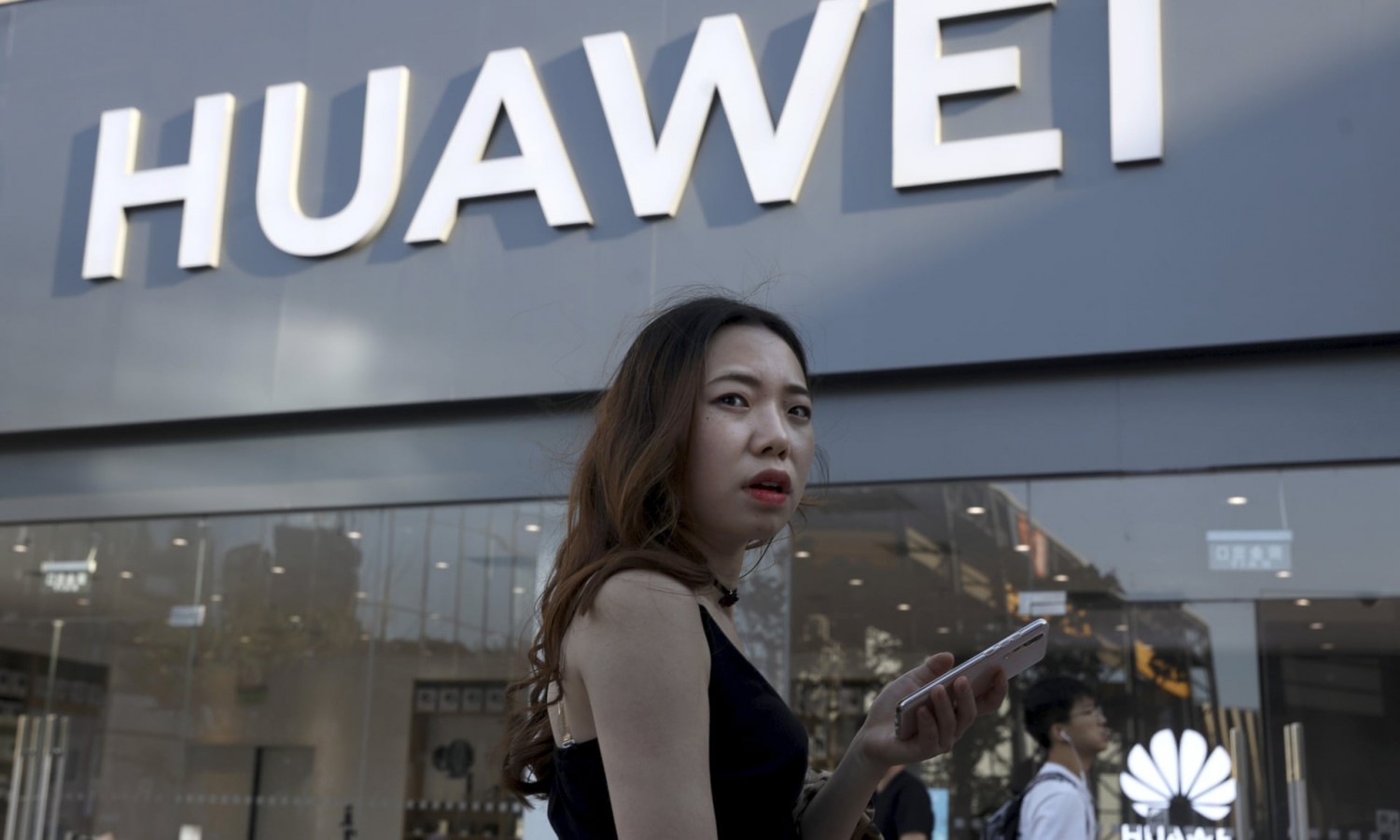 A woman uses a smartphone outside a Huawei store in Beijing Photograph: Ng Han Guan/AP