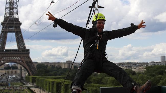 A participant rides a zip-line tied from the second floor of the Eiffel Tower, 115 metres above the Champ de Mars gardens along an 800-metre-cable, as part of a free event in Paris. Picture: AP Photo/Francois Mori.Source:AP