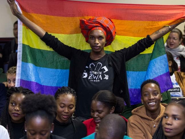An activist holds up a rainbow flag to celebrate inside Botswana High Court in Gaborone. Picture: AFPSource:AFP