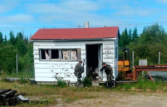 In this recent photo provided by the Royal Canadian Mounted Police, RCMP officers canvas homes and buildings in the Gillam, Manitoba area, as they continue to search for two teenagers being sought in the killings of three people in northern British Columb