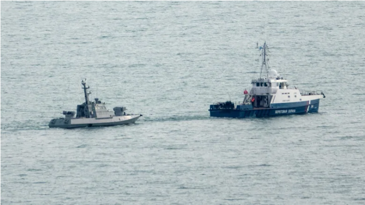 A seized Ukrainian ship is towed by a Russian Coast Guard vessel out of the port in Kerch, near the bridge connecting the Russian mainland with the Crimean Peninsula, on Sunday. (Alla Dmitrieva/Reuters)