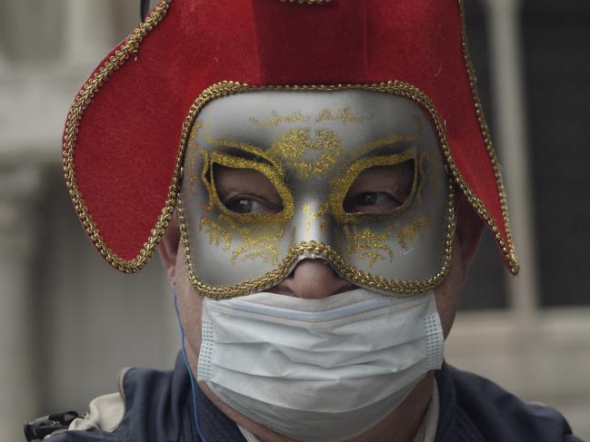 A Russian tourist dons both a carnival mask and a protective face mask as he visits St. Mark's square Venice. Picture: Photo/Renata Brito.Source:AP