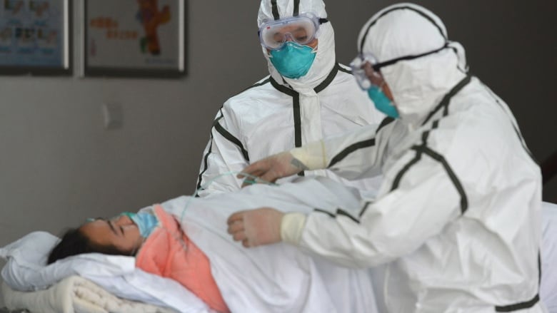 Medical workers in protective suits move a coronavirus patient into an isolation ward at the Second People's Hospital in Fuyang in central China's Anhui province on Saturday. (Chinatopix via The Associated Press)
