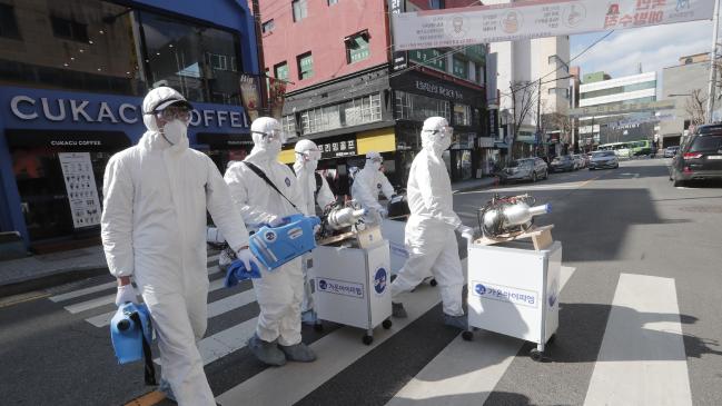 Workers arrive to spray disinfectant at a shopping street in Seoul, South Korea. Picture: AP Photo/Ahn Young-joon.Source:AP