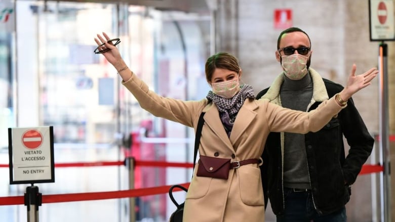 Passengers wearing protective face masks gesture in Milano Centrale railway station in Milan on Sunday, after millions of people were placed under forced quarantine in northern Italy to help curb the spread of the COVID-19 outbreak. (Miguel Medina�