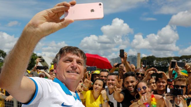 AFP / President Bolsonaro took selfie with supporters outside the presidential palace on Sunday despite government warnings against large gatherings