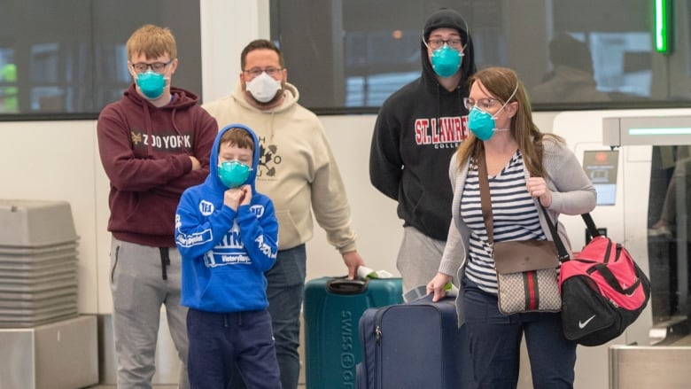 Travellers wear masks as they walk through Montreal's Trudeau Airport. (Ryan Remiorz/Canadian Press)