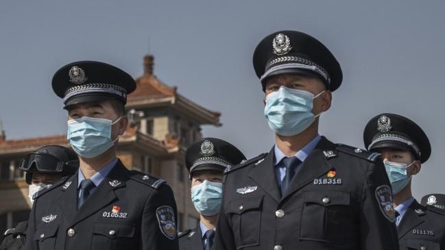 Chinese police officers wear protective masks as wait to observe three minutes of silence to mark the country's national day of mourning for COVID-19 in Beijing . Picture: Kevin Frayer/Getty Images.Source:Getty Images