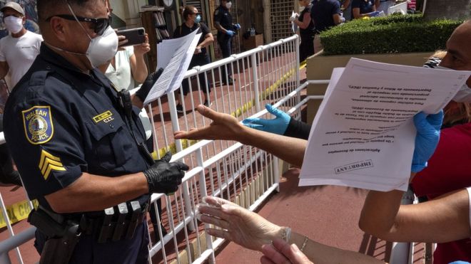 EPA / A police officer hands out unemployment benefit applications in a car park in Florida