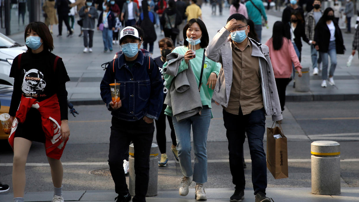 People wearing face masks are seen at a shopping area in Beijing, China on April 6, 2020. © REUTERS/Tingshu Wang