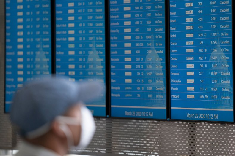 A man with a face mask looks at the board at Ronald Reagan Washington National Airport on March 29, 2020, in Arlington, Virginia. ALEX EDELMAN/AFP VIA GETTY IMAGES