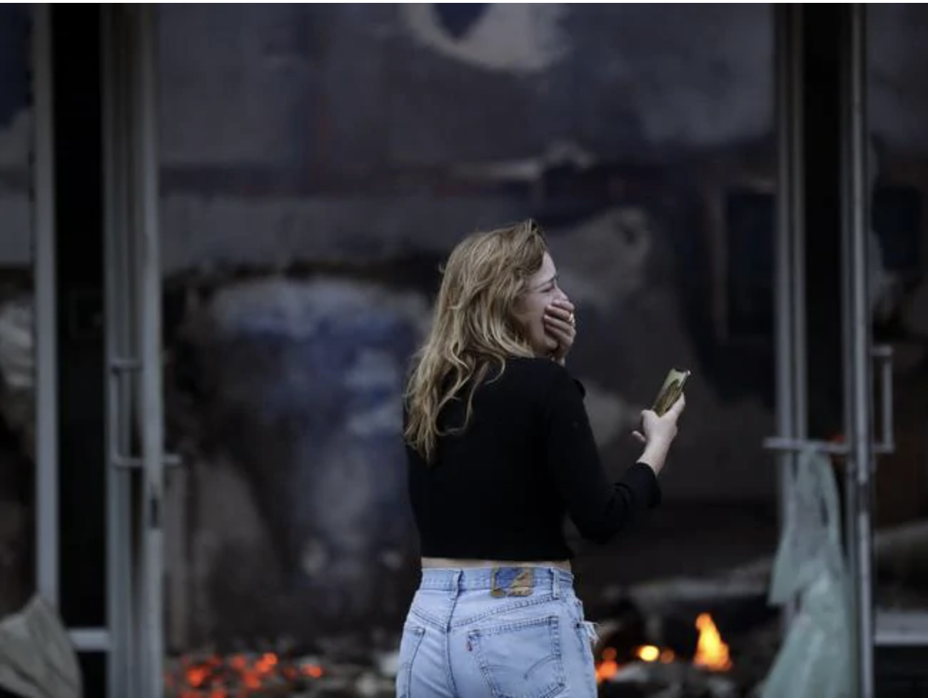 A woman cries as she watches a building burn after a protest over the death of George Floyd in La Mesa, Calif. Picture: Gregory Bull A woman cries as she watches a building burn after a protest over the death of George Floyd in La Mesa, Calif. Picture: Gregory BullSource:AP