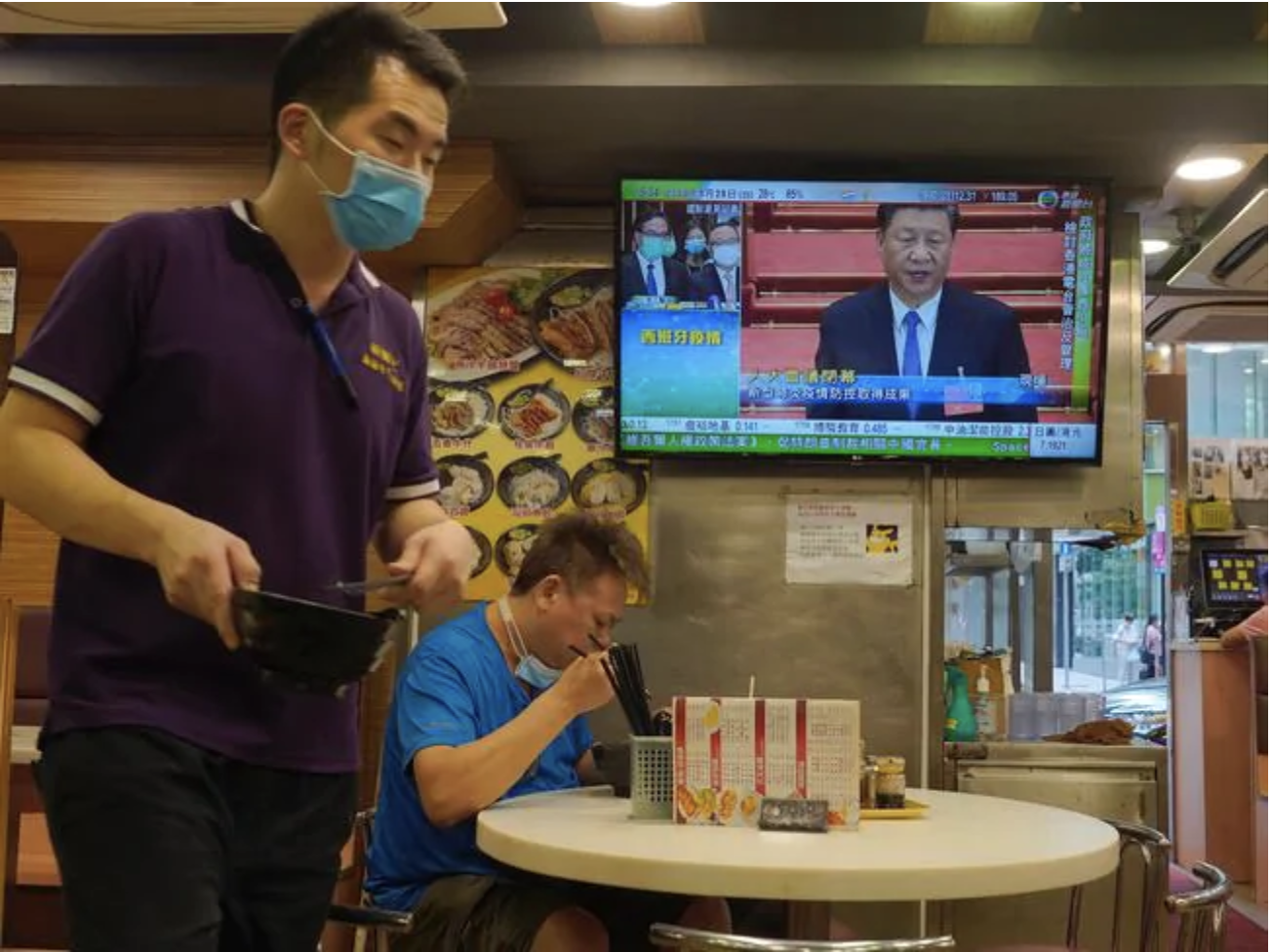  A man has lunch beneath a television showing live telecast of Chinese President Xi Jinping at the closing session of the National People's Congress, Picture: Vincent Yu/APSource:AP