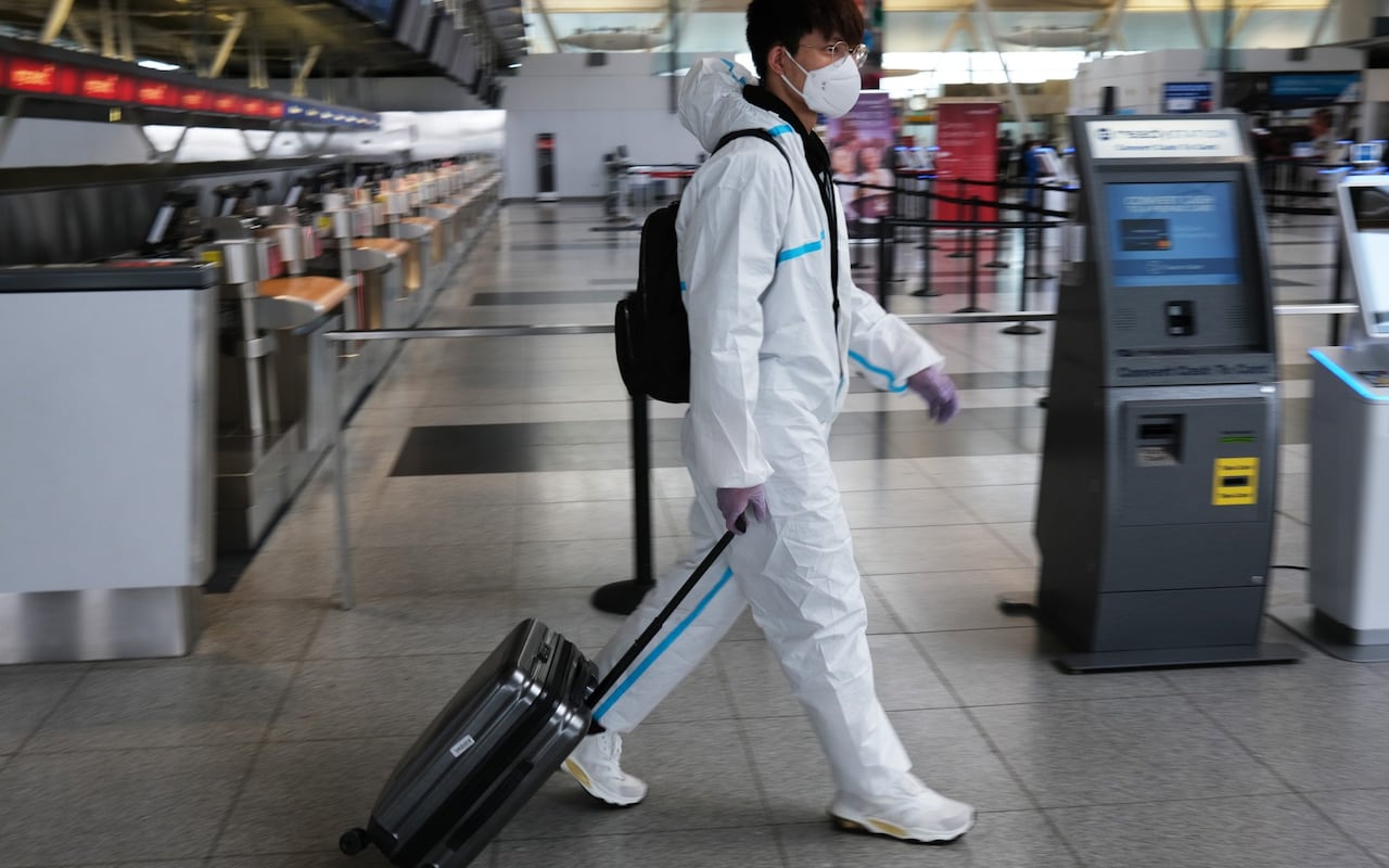 Travellers in protective gear walk through a deserted JFK airport in New York CREDIT: Getty